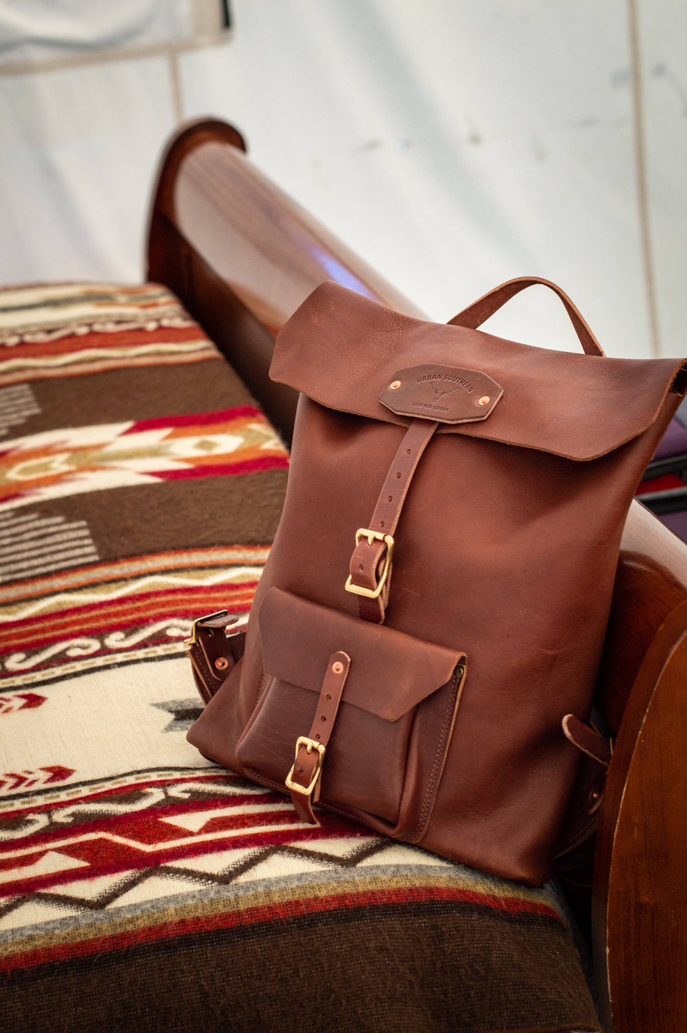 Brown leather backpack sitting on a bed