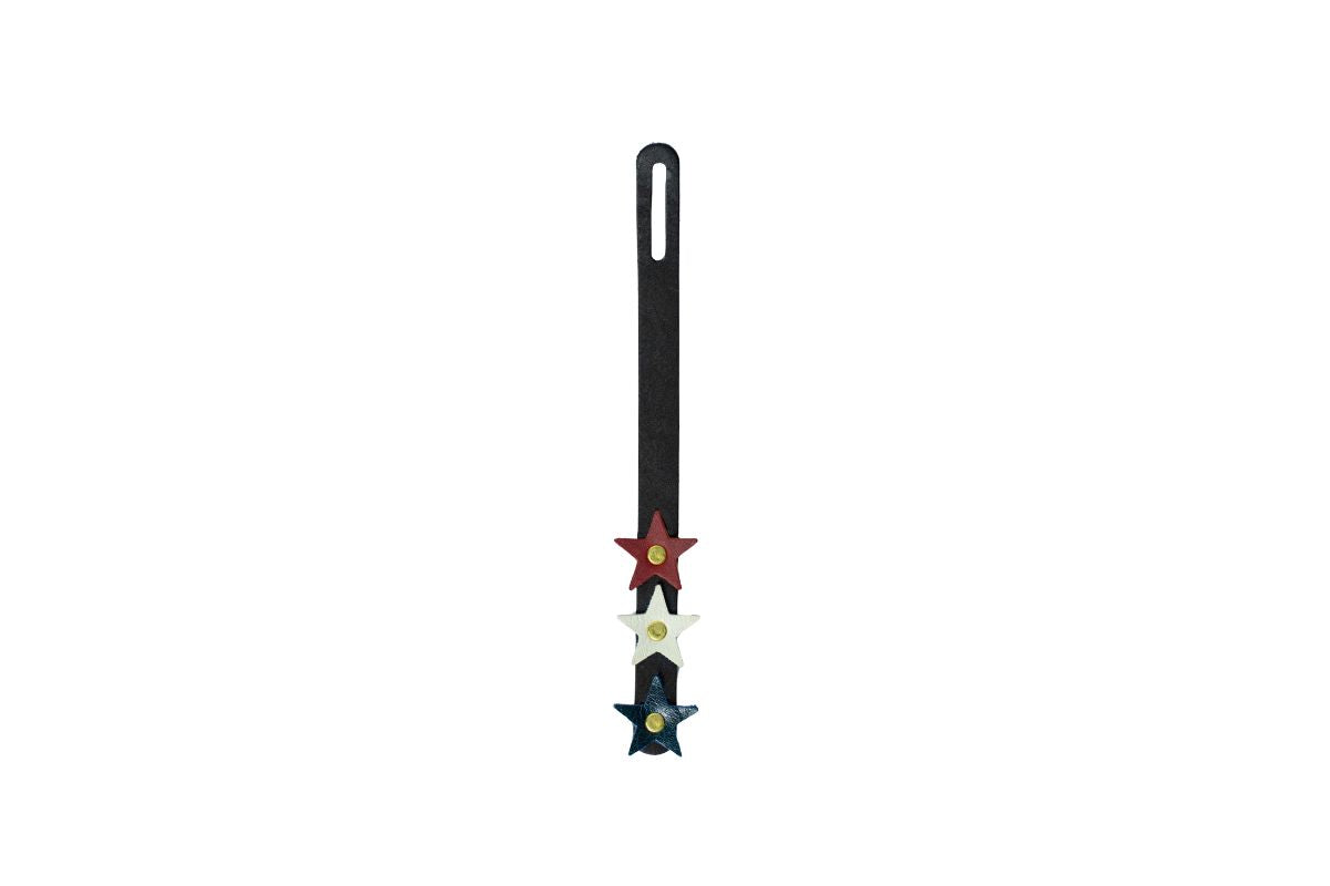 A black leather bag charm with red, white  blue stars on a white background. 