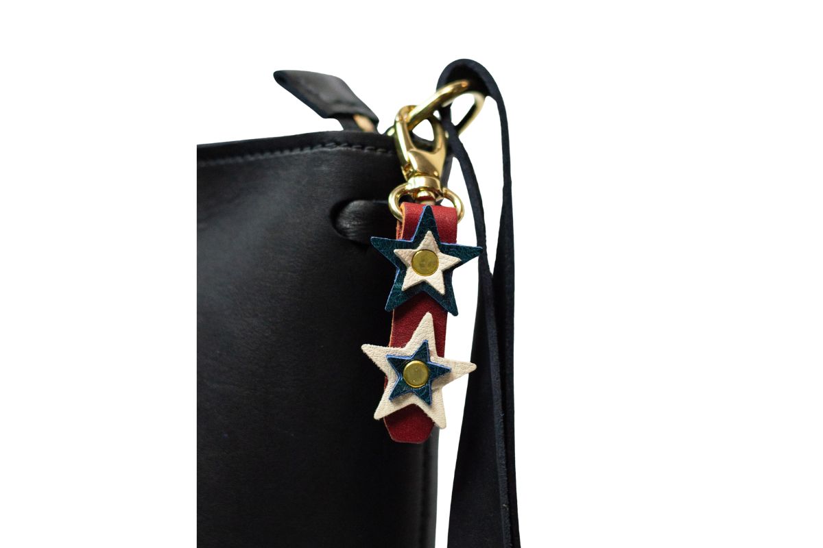 Black handbag with a decorative red, white & blue star charm on a white background