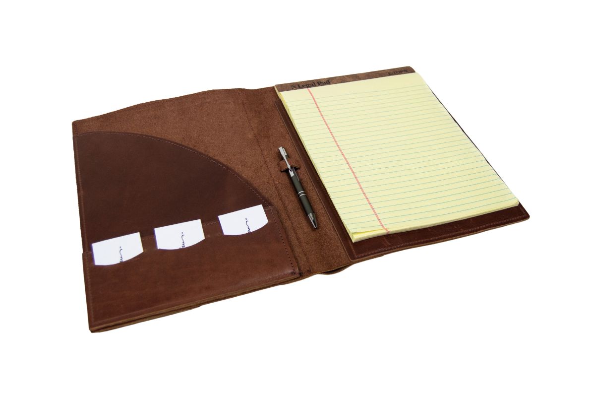 Brown leather portfolio with open pages showing lined paper and a pen on a white background
