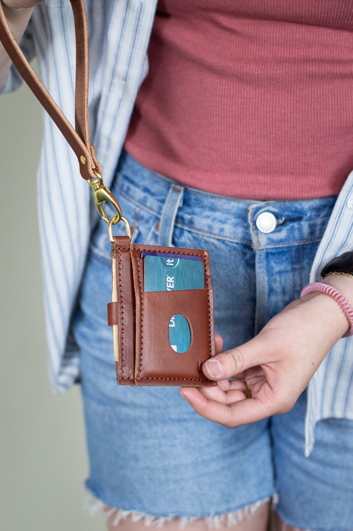A woman holds the Everly Wristlet Wallet in Chestnut Brown.