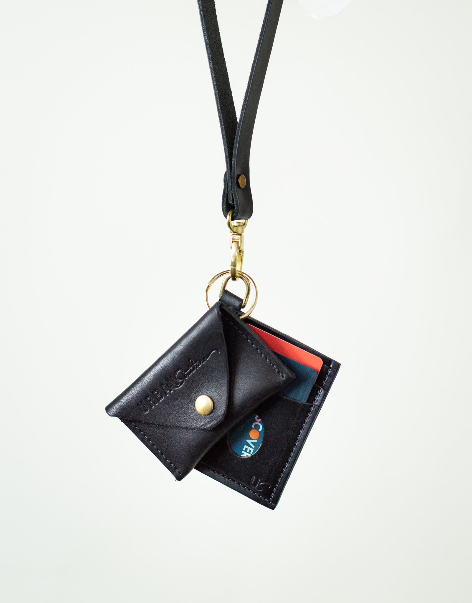 The Everly Wristlet Wallet in Black is shown with the Urban Southern Keychain Coin Purse attached to the wallet's leather strap.