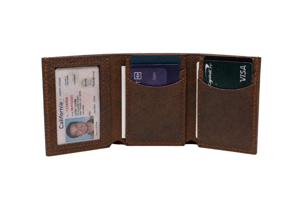 A brown leather trifold wallet lies open, the wallet is full of credit cards and a male drivers license is placed in the photo id window. 