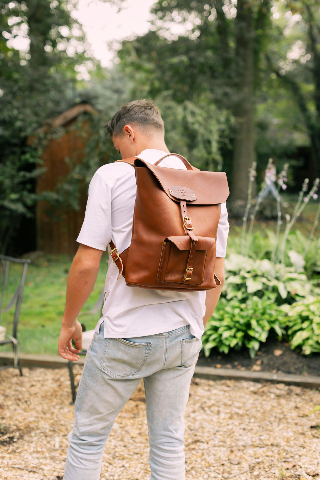 Man wearing a brown leather backpack in an outdoor setting