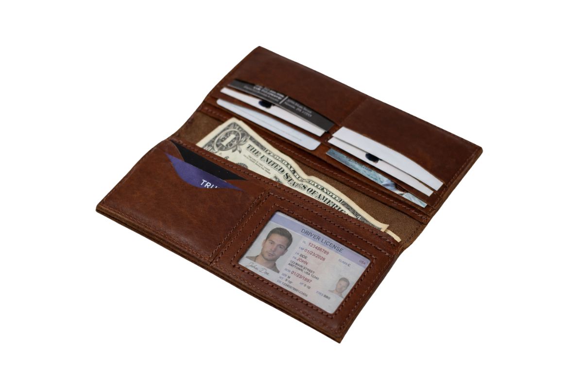 Interior of a cognac leather western wallet, with credit cards filling the 8 card slots, cash in one of the large middle compartments & a drivers license in the id window. 