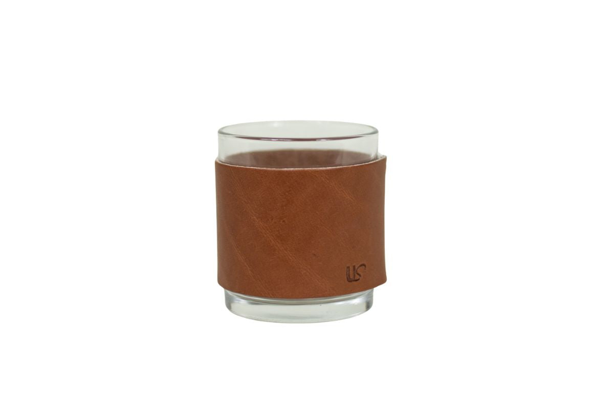 Whiskey glass with a brown leather sleeve, a small us logo on the bottom corner