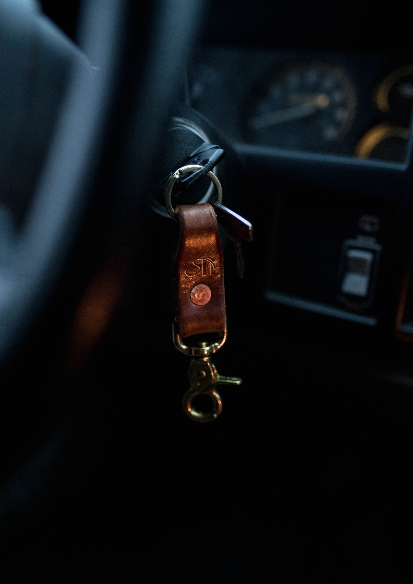 Leather keychain with keys attached to a car's ignition inside a vehicle