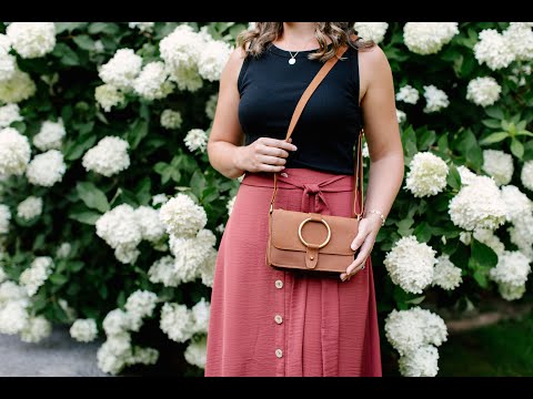 Video tour demonstrating the features of the 5-Pocket Crossbody. A woman is showcasing the brass post closure & ring details on the front of the bag, as well as the 5 interior pockets and credit card slots. 