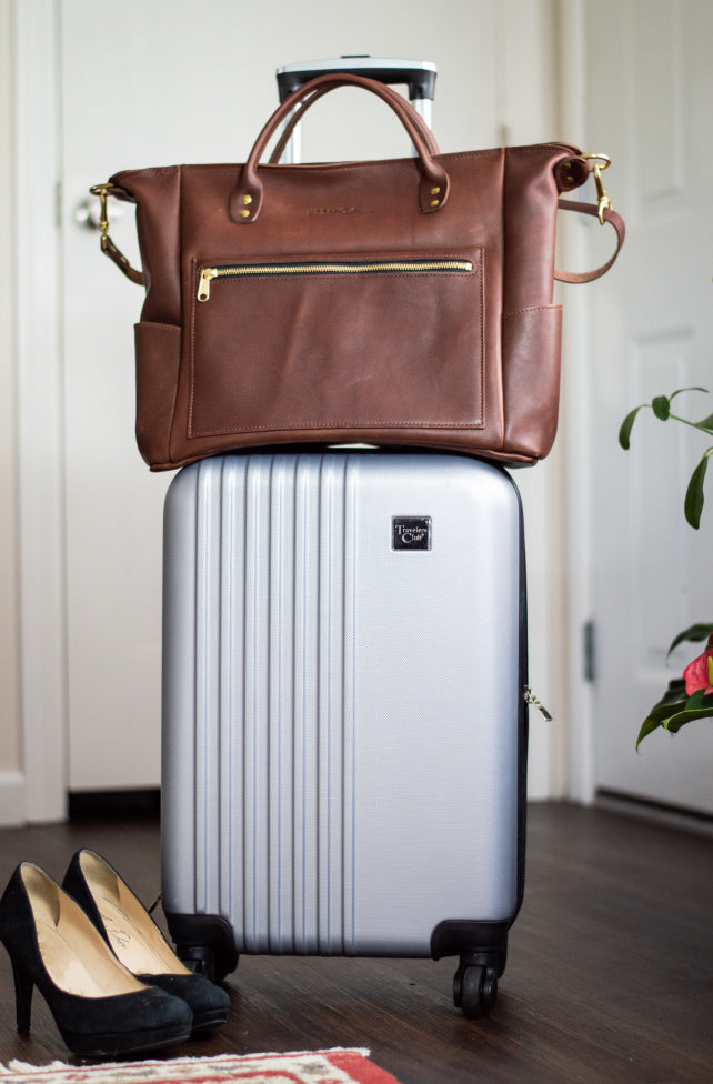 The Legacy Voyager bag sits on top of a carry-on piece of luggage. 