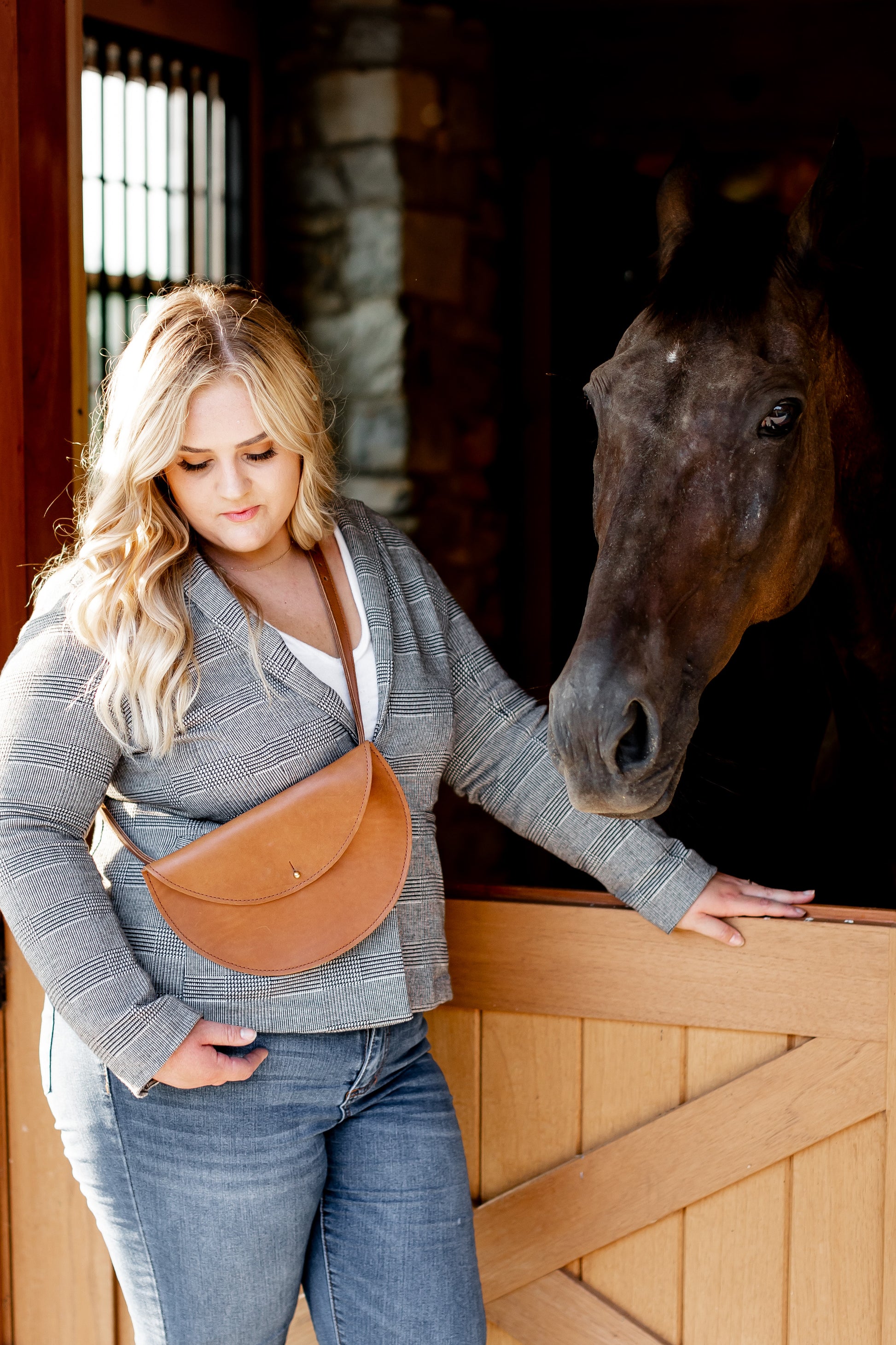 A woman wears the Half Moon Belt Bag in Honey across her shoulder like a crossbody bag. 